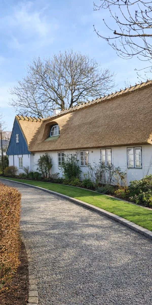 White thatched cottage with curved gravel drive